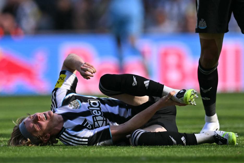 Anthony Gordon of Newcastle United in pain on the field after an injury.