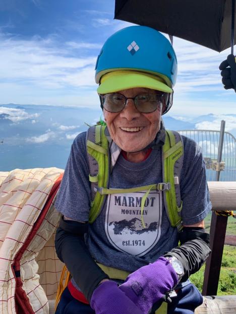 Smiling older man atop Mount Fuji.
