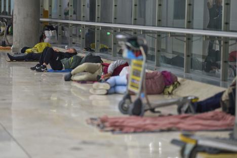 People sleeping on the floor of an airport terminal.