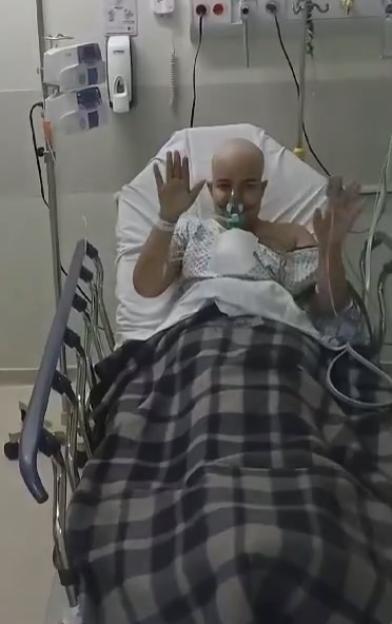 Woman in hospital bed waving.