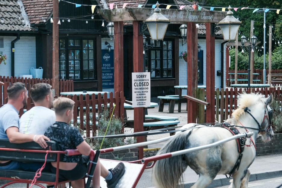 A horse-drawn carriage passes a closed restaurant.