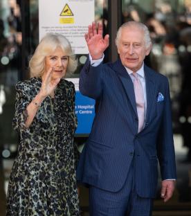 King Charles III and Queen Camilla waving at University College Hospital Macmillan Cancer Centre.
