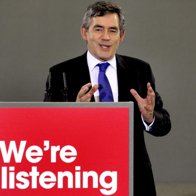 Gordon Brown speaking at a podium that reads "We're listening".