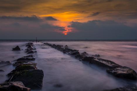 Sunset over a rocky jetty.