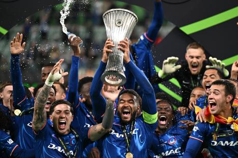 Chelsea FC players celebrating with the UEFA Conference League trophy.