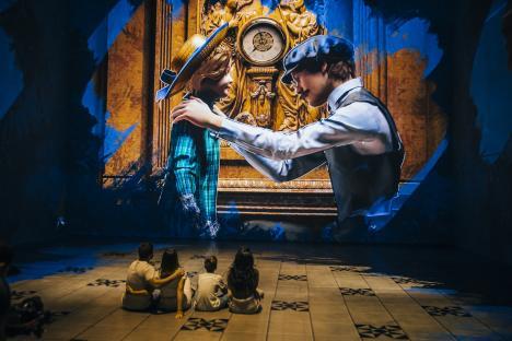 A family watches a large projection of a man and child at a Titanic exhibition.