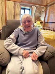Julie Goodyear, actress known for playing Bet Lynch, smiling in a chair.