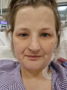 Close-up of a woman in a hospital bed with an IV line.