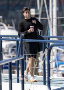 James Argent walking at a marina, holding a coffee cup.