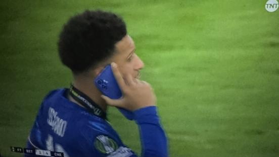 Man in blue jersey using a blue phone.