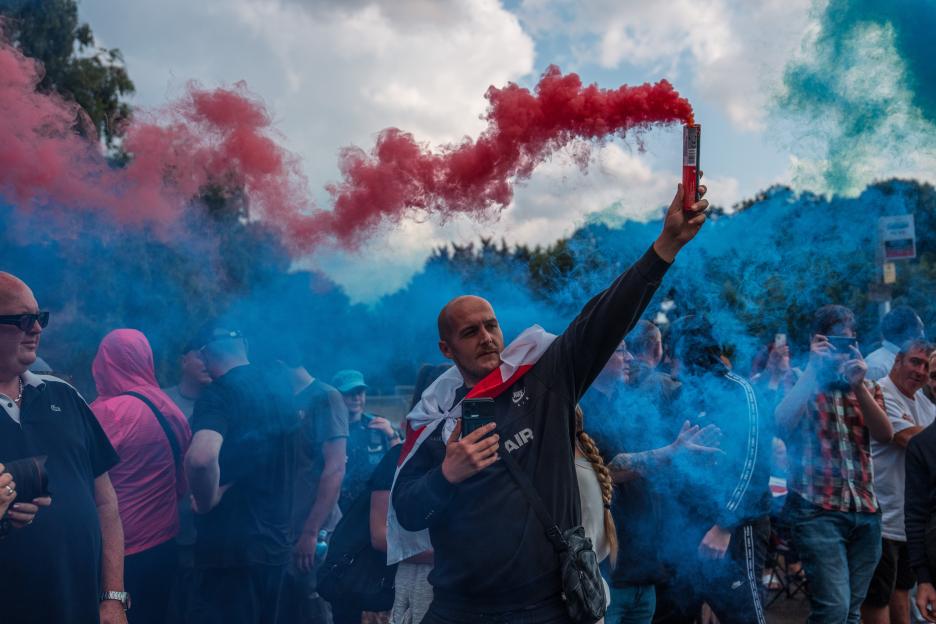 Protestor ignites red and blue smoke flares at a demonstration.