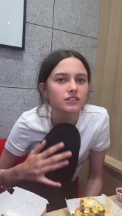 Teenage girl talking while eating a burger.