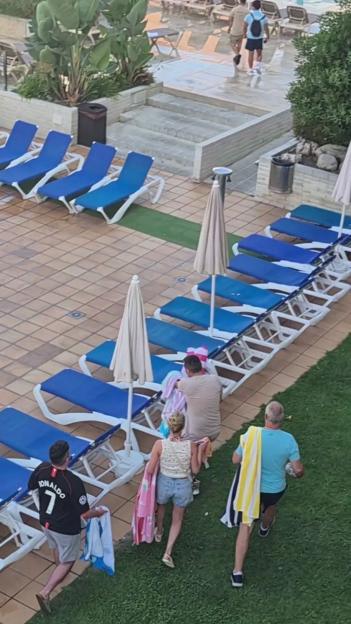 People reserving sunbeds at a pool.