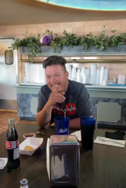 A smiling man sitting at a table in a restaurant.