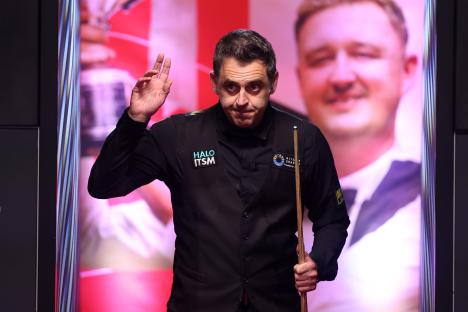Ronnie O'Sullivan at the snooker table, waving.