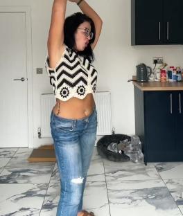 Woman in a crocheted top and jeans dancing in a kitchen. Text overlay: