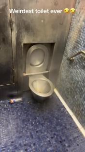 A stainless steel toilet in a restroom.