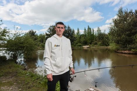 Phil Foden fishing by a pond.