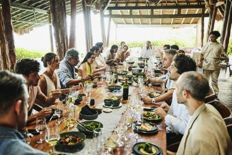 Large group of people dining outdoors at a long table.