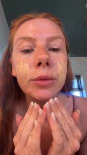 Person applying foundation to their face.