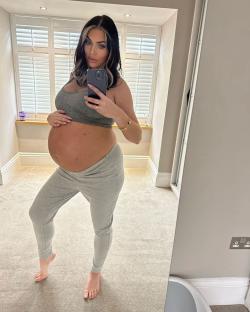 Pregnant woman taking a selfie showing her baby bump.