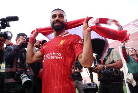 Mohamed Salah celebrates, holding a Liverpool scarf.