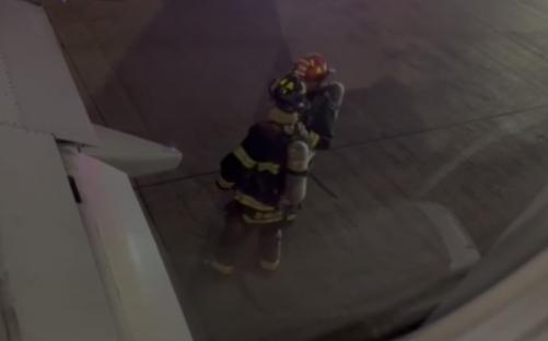 Firefighter assisting someone near an airplane.