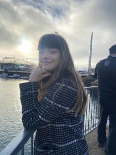Woman in a black and white coat by the water.