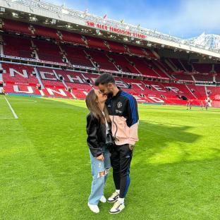 Couple kissing in front of Old Trafford stadium.