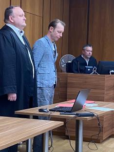 Courtroom scene with three men; one defendant and two others.