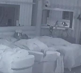 Low-light image of two people in bed.