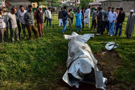 Debris of a military aircraft crash surrounded by onlookers.