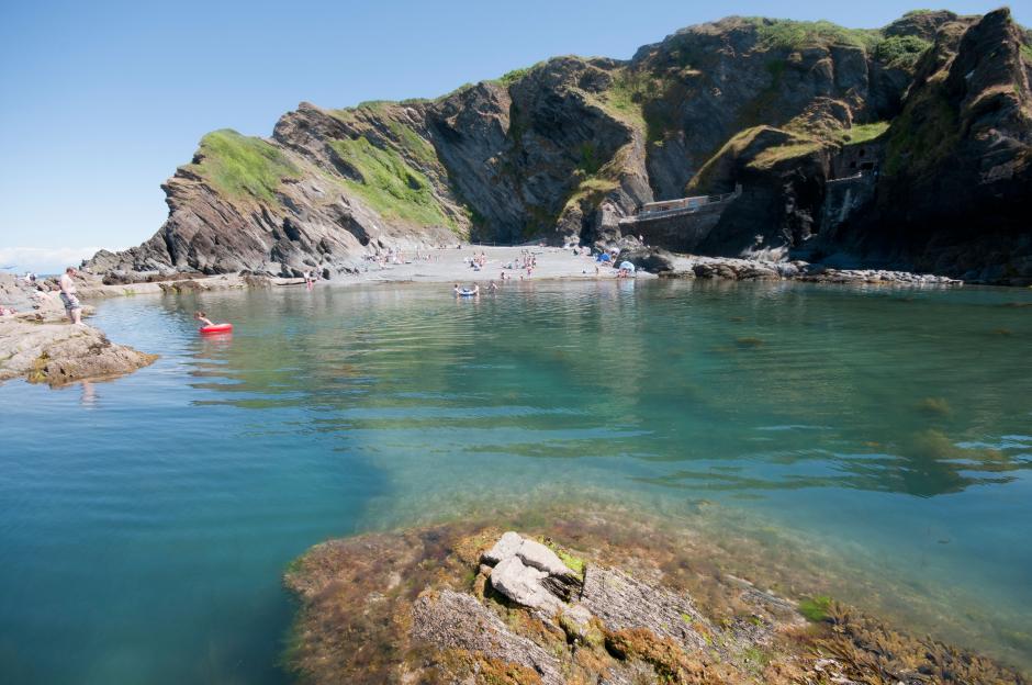 Tunnels Beach rock pool in Ilfracombe, North Devon, with people swimming and sunbathing.