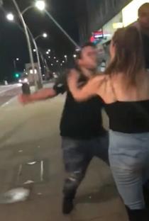 Man punching woman on street at night.