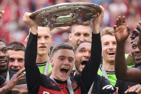 Florian Wirtz of Bayer Leverkusen lifts the Bundesliga championship trophy.