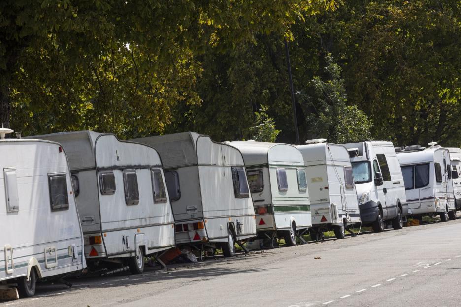 Caravan parked on the roadside with bags of belongings on the grass.
