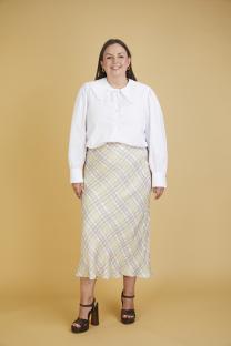 Woman wearing a white collared shirt and a pastel plaid midi skirt.
