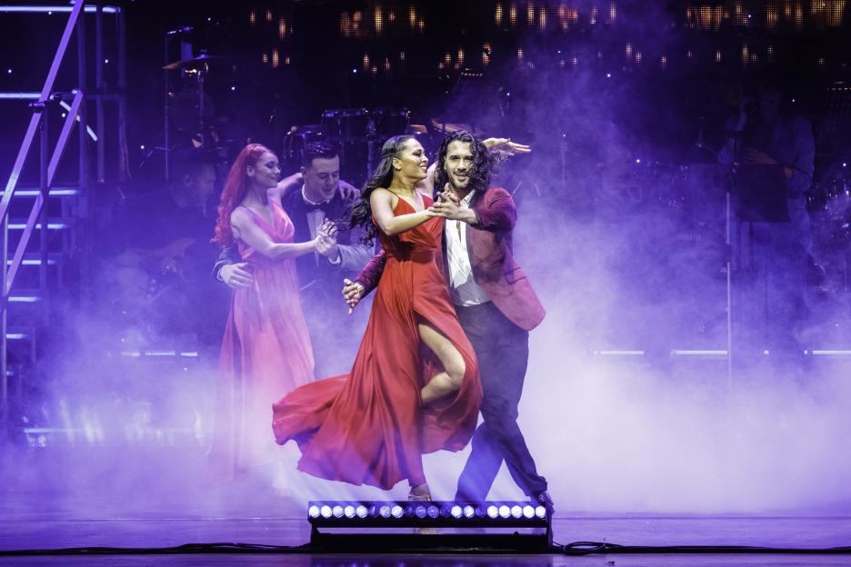 Nine "Strictly Come Dancing" professionals posing in dance attire with a large disco ball and show title in the background.