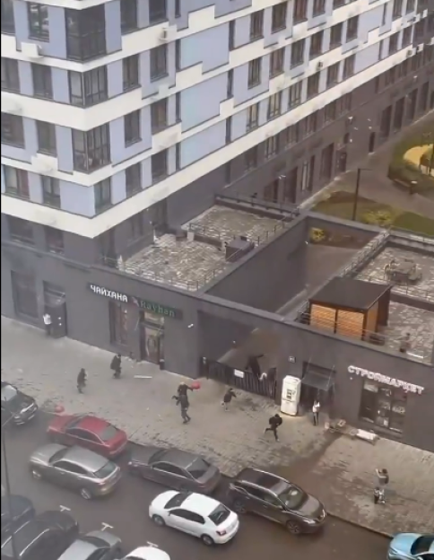 People running on the street during an explosion outside a building.