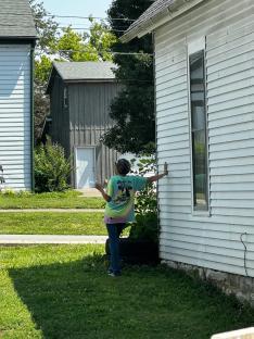 Person standing outside near a house and sheds.