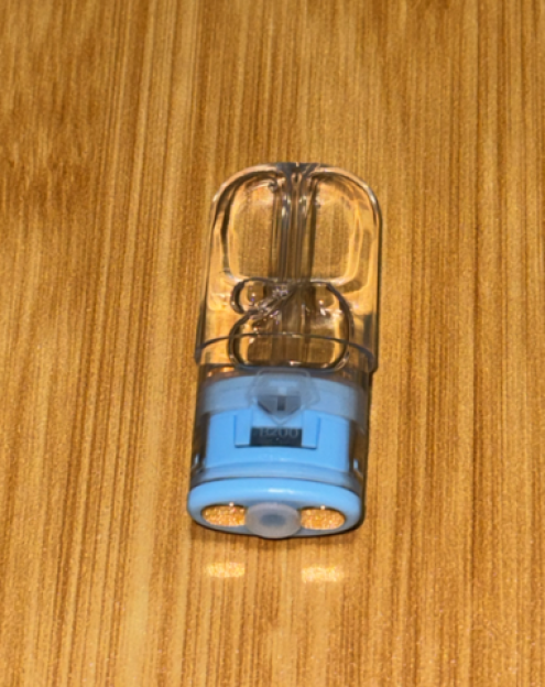 Small clear and blue medical device on a wooden surface.