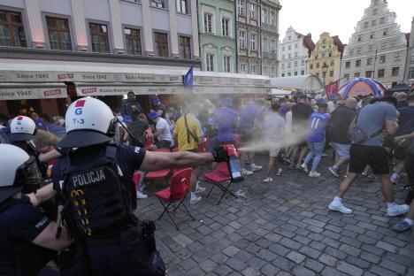 Police officer spraying tear gas at soccer fans.