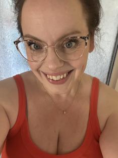 Self-portrait of a woman wearing glasses and a red tank top.