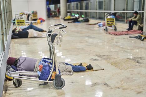 Homeless people sleeping on the floor of an airport terminal.