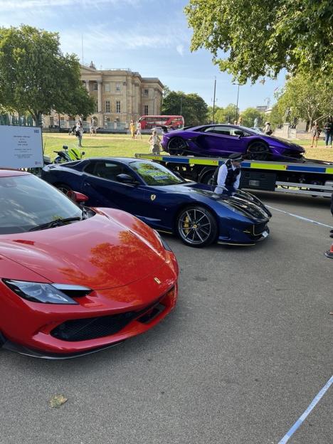 Seized luxury cars, including two purple Lamborghinis, impounded by police.