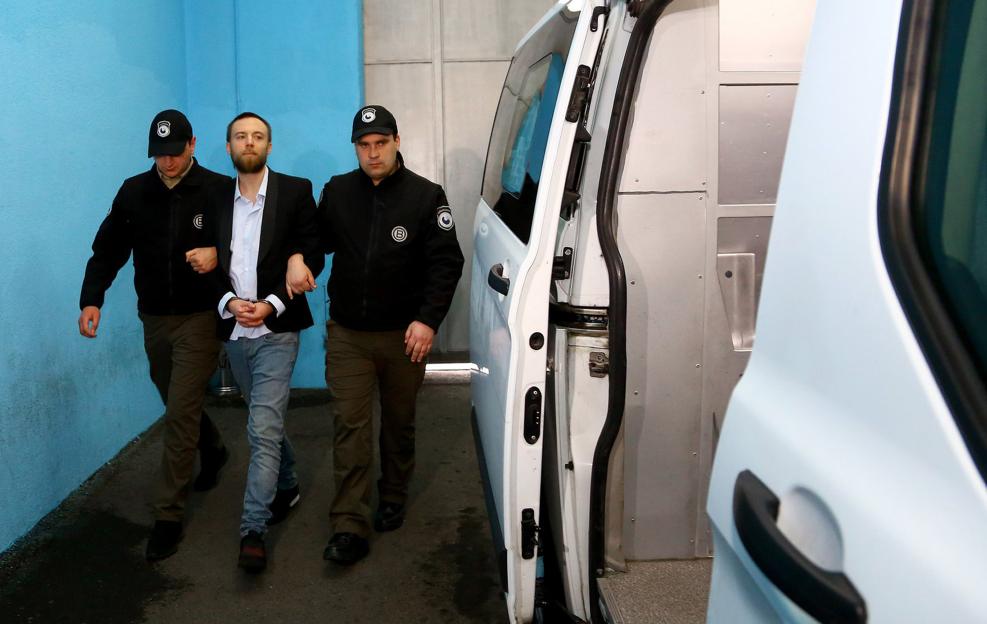 Jack Shepherd being led to a police van by two officers.