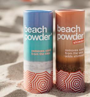 Two containers of Beach Powder, one regular and one shimmer, on a sandy beach.
