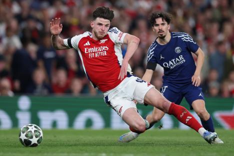 Declan Rice of Arsenal being fouled by Vitinha of Paris Saint-Germain during a soccer match.