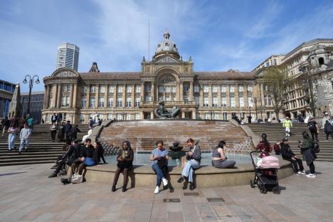 People relaxing by a fountain in Birmingham city center on a warm spring day.