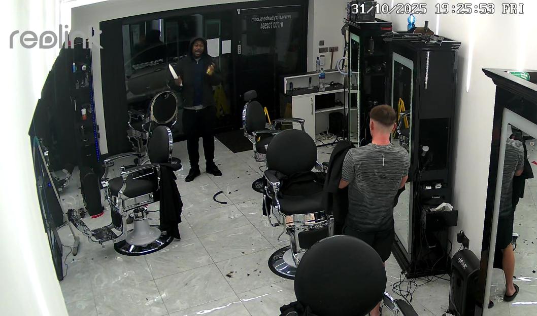 A man in a black jacket holding a knife in a barbershop.